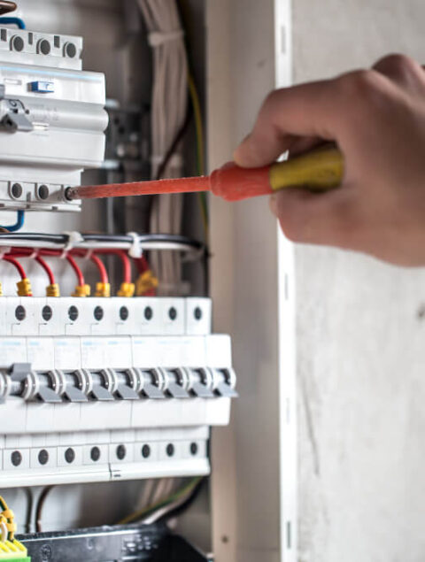 man-electrical-technician-working-switchboard-with-fuses-installation-connection-electrical-equipment-close-up (1)